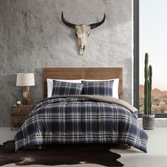 a bed room with a neatly made bed and a cow skull on the wall