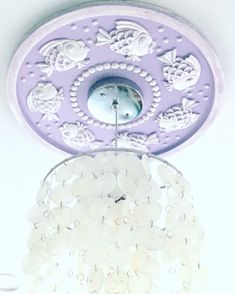 a chandelier hanging from the ceiling in a room with white and purple decorations