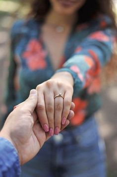 a woman holding the hand of a man who is wearing a ring on his finger