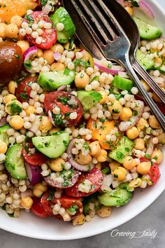 a white bowl filled with corn, cucumber and tomatoes