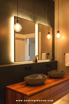 a bathroom with two sinks and lights on the wall above them, along with a large mirror