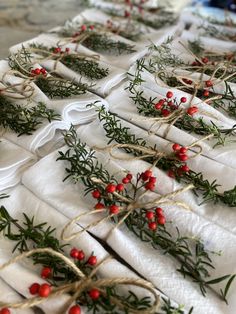 the table is covered with white napkins and tied with twine, red berries and green leaves