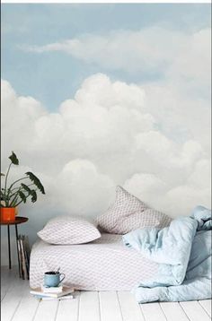 there is a bed with pillows and blankets on it in front of a cloudy sky