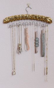 a gold and white wind chime hanging from a hook on a wall with beads