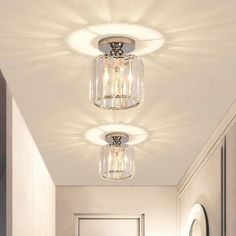 two lights that are hanging from the ceiling in a hallway with white walls and flooring