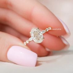 a woman's hand holding a ring with a white diamond on the middle of it