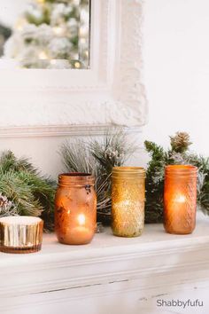 candles are lined up on a mantle with pine cones and evergreen branches in the background