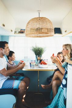 the family is sitting at the table eating and drinking watermelon in the kitchen