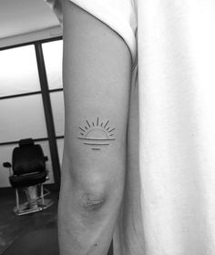 a person with a small sun tattoo on their left arm and the other arm behind them