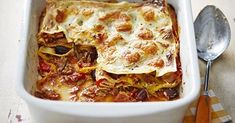 a casserole dish with meat, cheese and vegetables in it next to a spoon