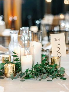 a table with candles and greenery on it