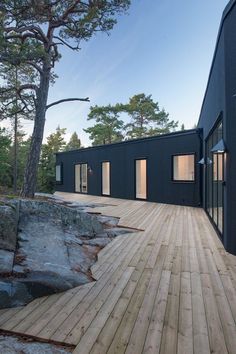 the house is made out of black wood and has large windows on one side, with sliding glass doors on the other