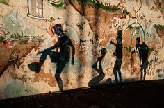 the shadows of people are cast on a wall that has been vandalized with graffiti