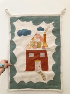 a person holding up a piece of art that looks like a house with a chimney