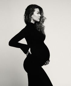 a pregnant woman poses for a black and white photo with her hands on her hips