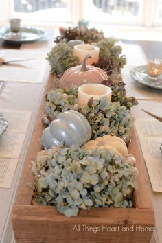 a long wooden table with candles and succulents on the top, along with other place settings