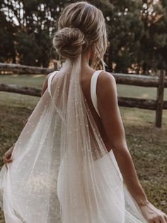 the back of a woman wearing a white wedding dress with sheer, beaded detailing