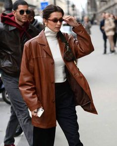 Bella Hadid Brown Leather Coat The fashion icon and diva, Bella Hadid, is the most popular and highly influential supermodel of our generation. Being the source of style inspiration, Bella showcases the off-duty model aesthetic like no other, making her outfits effortlessly chic and trendsetting. Introducing the epitome of urban sophistication with our Bella Hadid brown oversized leather coat, an ultimate wardrobe essential and the perfect addition to your outerwear collection. Striking the perfect balance between casual and formal, this brown leather coat can be effortlessly styled with daily outfits or for important events, showcasing its versatility. Crafted to perfection using premium-quality 100% real leather, this brown jacket is highly durable against winds, scratches, and external Oversized Leather Coat, Brown Jacket Outfit, Brown Leather Jacket Outfit, Collarless Leather Jacket, Red Jacket Leather, Celebrity Inspired Outfits, Brown Leather Coat, Blue Leather Jacket, Leather Jacket With Hood