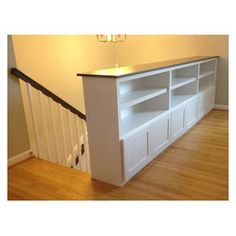 a white entertainment center sitting on top of a hard wood floor next to a banister