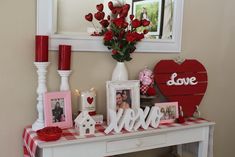 valentine's day decorations on a white table with red candles and flowers in vases