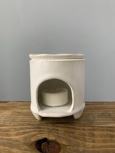 a white candle holder sitting on top of a wooden table