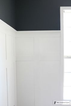 an empty room with white paneling and black walls