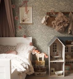 there is a doll house next to a bed in the room with flowers on it