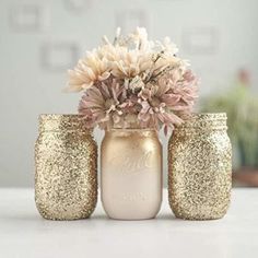 three jars with flowers in them sitting on a table