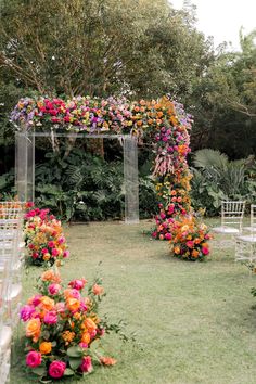 an outdoor wedding setup with flowers and chairs in the grass, surrounded by greenery