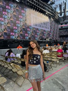 a woman standing in front of a stage wearing a skirt and crop top with stars on it