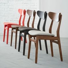 four chairs with different colored seats in front of a white brick wall and flooring