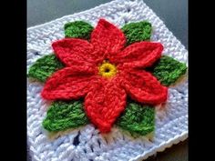 a crocheted square with a poinsettia on the center and green leaves