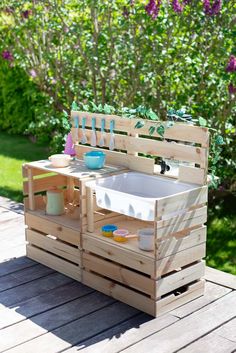 an outdoor sink made out of wooden pallets on a deck with purple flowers in the background