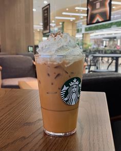 a cup of coffee with whipped cream on top sits on a table in a restaurant