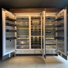 an open refrigerator with lots of wine bottles in it's door and shelves on both sides