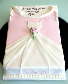 a cake that is shaped like a dress and has flowers on the bottom, along with writing