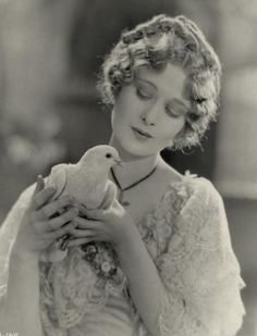 an old photo of a woman holding a bird