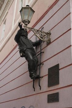 a statue is attached to the side of a building with a street light on it