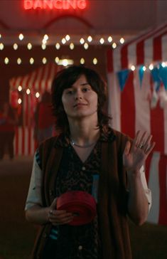 a woman standing in front of a circus tent holding her hands up to the side