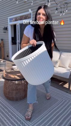 a woman holding a large white pot on top of a patio