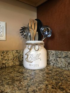 a mason jar with spoons and utensils in it sitting on a counter