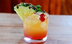 a pineapple and cherry cocktail with garnish on the rim