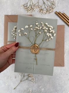 a hand holding a card with flowers on it and some gold foil in the middle