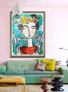 a living room filled with furniture and a painting hanging on the wall over a green couch