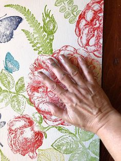 an old woman's hand on a flowered wallpaper with butterflies and flowers