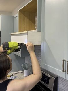 a woman using a power drill to install cabinets