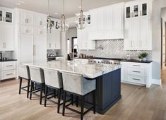 a large kitchen with white cabinets and marble counter tops, along with bar stools