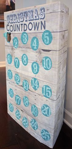 a wooden calendar sitting on top of a hard wood floor next to a white wall