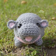 a crocheted stuffed animal sitting in the grass with it's mouth open