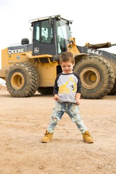 a young boy standing in front of a bulldozer